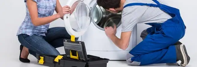 Washer repair technician inspecting a front-load washing machine with tools in South Bend, IN
