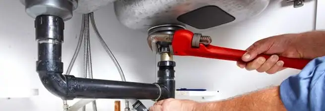 Garbage disposal repair technician tightening the sink drain and disposal connection in South Bend, IN