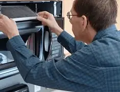 Appliance repair technician replacing a microwave vent filter in South Bend, IN