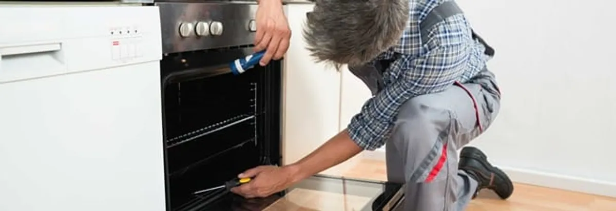 Oven repair technician inspecting and servicing an electric oven in South Bend, IN