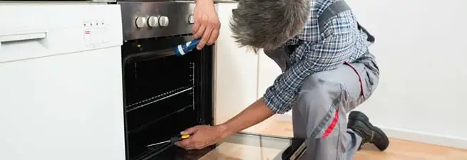 Oven repair technician inspecting and servicing an electric oven in South Bend, IN