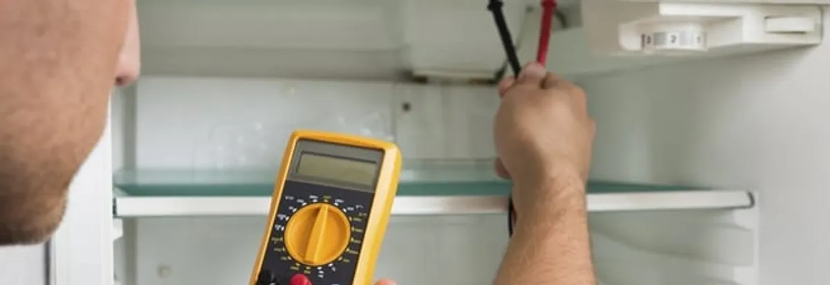 Refrigerator repair technician testing electrical components with a multimeter in South Bend, IN