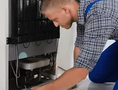 Refrigerator repair technician servicing the compressor and condenser area in South Bend, IN