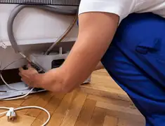 Appliance repair technician fixing refrigerator water line and connections in South Bend, IN