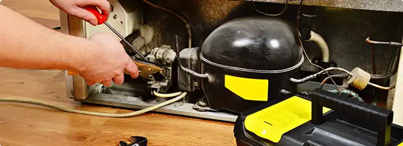 Refrigerator repair technician fixing the compressor and wiring in South Bend, IN