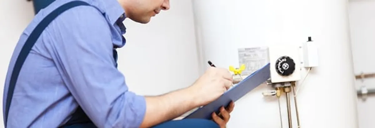 Water heater repair technician inspecting the unit and recording service notes in South Bend, IN