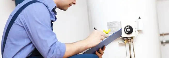 Water heater repair technician inspecting the unit and recording service notes in South Bend, IN