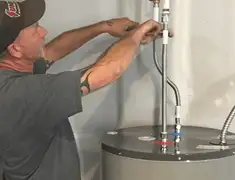 Water heater repair technician tightening supply line connections in South Bend, IN