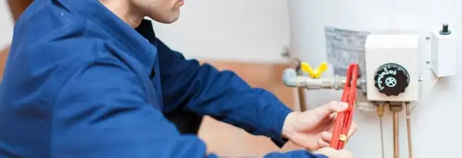 Water heater repair technician adjusting the temperature control and gas valve in South Bend, IN